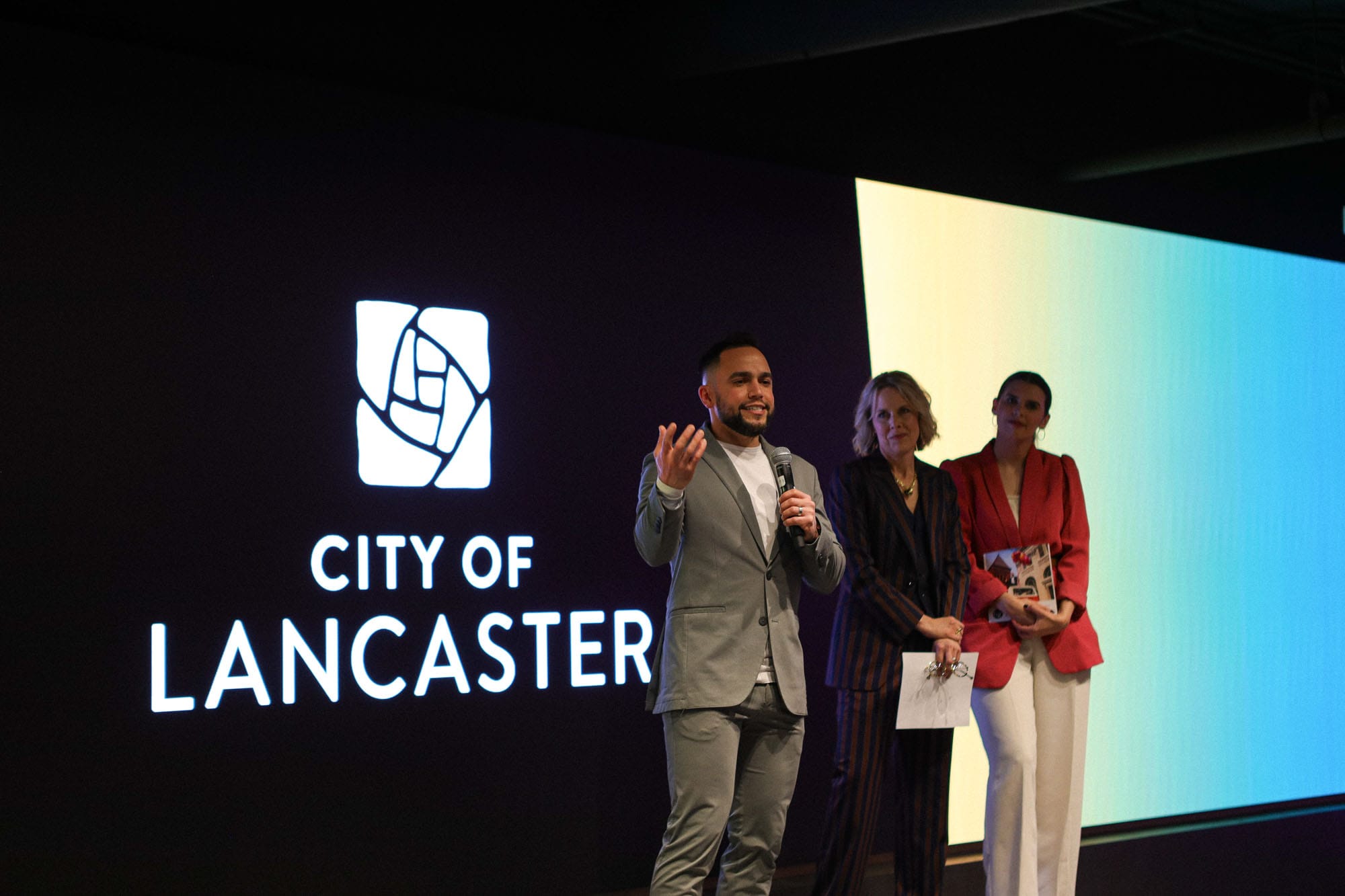 Commons on Vine-1 People speaking at Lancaster County Convention Center event with City of Lancaster logo.